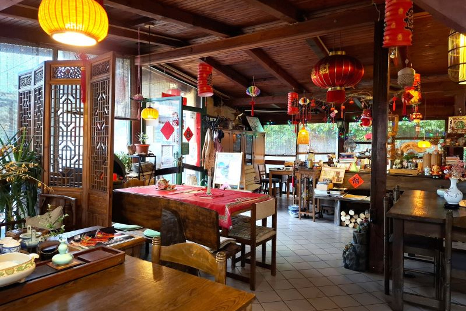 Unutrašnjost čajane Jing Yuan s drvenim stolovima i crvenim lampionima